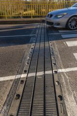 Car crossing an expansion joint in the asphalt of the road on a bridge