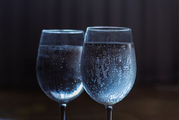 Crystal glasses with cold water. Dark morning room background. Sobriety concept. Sparkling water transparent glassware.