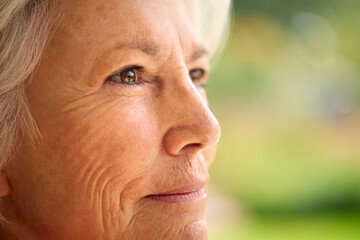 Close Up Portrait Of Senior Woman At Home With Garden In Background