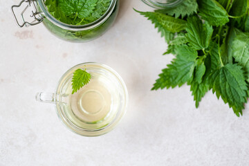 Herbal nettle tea with fresh nettle leaves in a glass cup on a table. Weight loss and detox....