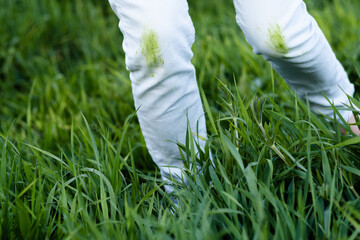 Close up dirty grass stains on white clothes. An unrecognizable person with green knees on a green...