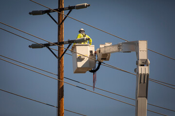 A Man on a manlift working on high electricity lines on a transmission pole
