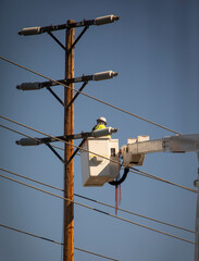 A Man on a manlift working on high electrcity lines on a transmission pole
