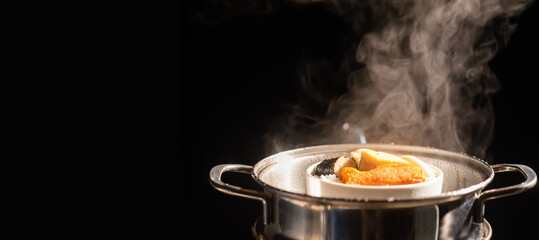 A boiling pot steams up as a chef cooking steam food in steam pot in a restaurant.	