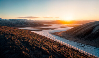 A winding river flows through a valley with snow-covered mountains in the background. 
