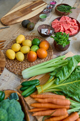 This vibrant image showcases a wooden table covered with an assortment of fresh fruits and vegetables. Highlighted are citruses like lemons and oranges, greens, and root vegetables. 