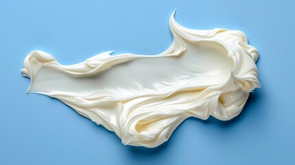   A detailed view of a bluish background bearing a mound of creamy substance, with a solitary droplet of water poised above its center