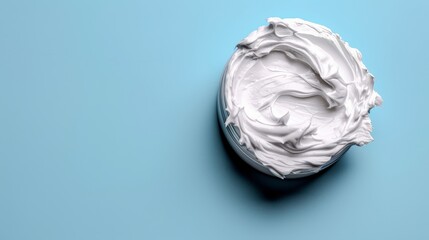   A bowl of whipped cream atop a light-blue surface A spoon sits in the center