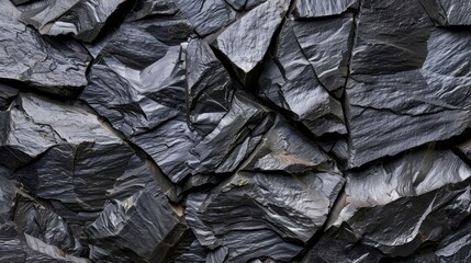   A sizable collection of black rocks assembled together on top of an adjacent pile of similar-hued rocks - obrazy, fototapety, plakaty