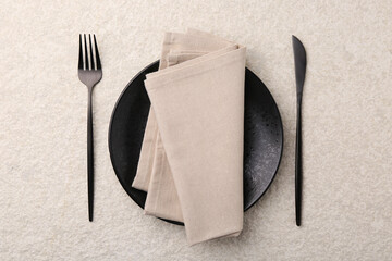 Stylish setting with elegant cutlery on beige textured table, top view