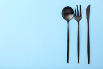 Stylish cutlery set on light blue table, flat lay. Space for text