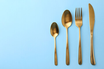 Stylish cutlery set on light blue table, flat lay. Space for text