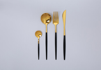 Stylish golden cutlery set on gray background, flat lay