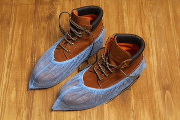 Men`s boots in blue shoe covers on wooden floor