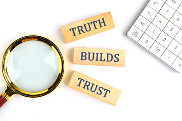 Truth builds trust symbol. Concept words Truth builds trust on wooden blocks on a white background near a calculator and a magnifying glass