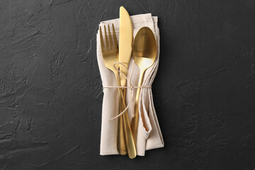 Set of stylish cutlery and napkin on black table, top view