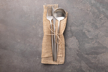 Set of stylish cutlery and napkin on grey textured table, top view