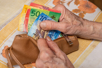 A pensioner from Switzerland looks at the contents of her wallet, Swiss francs, Costs of living in...
