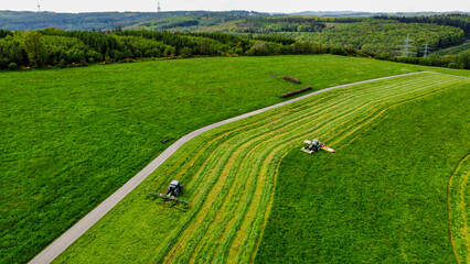Landwirte mähen eine Wiese und wenden das Gras (Luftaufnahme)