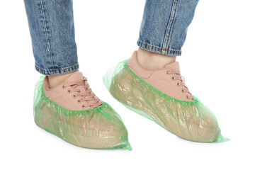 Woman wearing green shoe covers onto her sneakers against white background, closeup