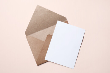 Letter envelope and card on beige background, top view. Space for text