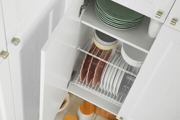 Clean plates and bowls on shelves in cabinet indoors