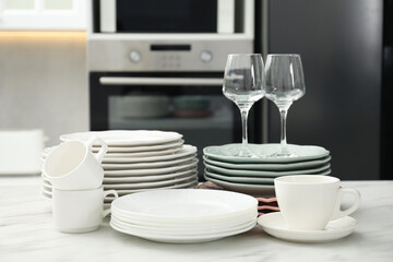 Fototapeta premium Clean plates, cups and glasses on white marble table in kitchen