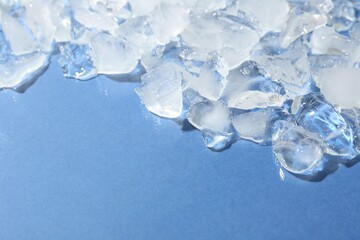 Pieces of crushed ice on light blue background, above view. Space for text