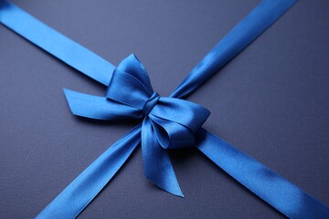 Bright satin ribbon with bow on blue background