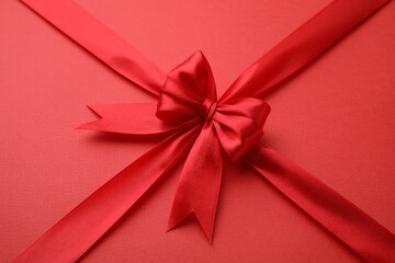 Bright satin ribbon with bow on red background