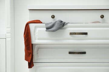 Cluttered chest of drawers indoors. Clothes in mess