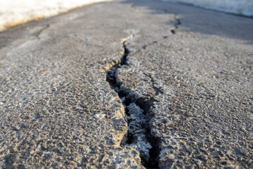 Close-up of cracks in the asphalt pavement, sidewalk in perspective, damage to the road surface in...