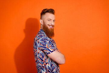Side profile photo of virile friendly man wear print shirt holding arms crossed smiling isolated on vibrant orange color background