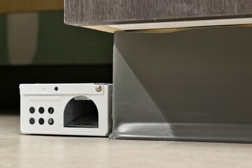 Rodent bait station poison pest control skirting board floor indoors concept.