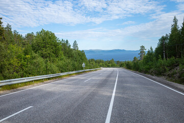 summer panoramic view of the highway among the hills with forest on the background of the sea and blue sky with clouds