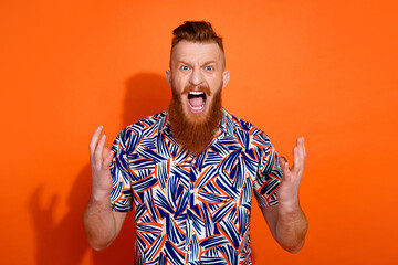 Photo of furious mad guy dressed print shirt shouting you empty space isolated orange color...