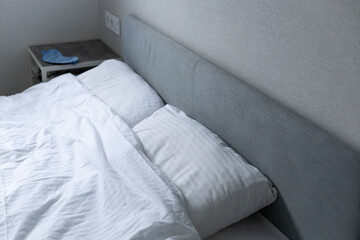 bedroom, bed with white bed linen, blue sleep mask on the back of the bed, sleep concept