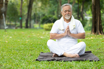 Obraz premium asian senior man meditating and doing yoga in the park