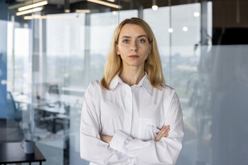 Confident businesswoman standing arms crossed in office