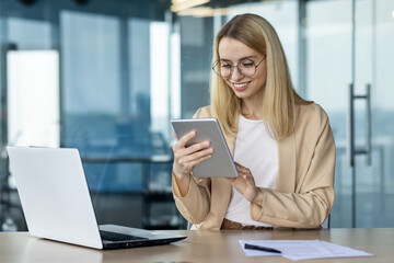 Professional woman using tablet and laptop in modern office