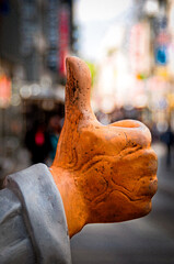 Artificial hand with thumb up on figure in pedestrian zone. 