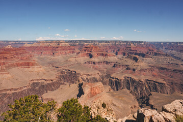 Panoramic view of Grand Canyon, Arizona, USA. Capturing stunning layers of red rock, deep gorges, greenery, and clear blue skies. Popular tourist destination renowned for immense scale.