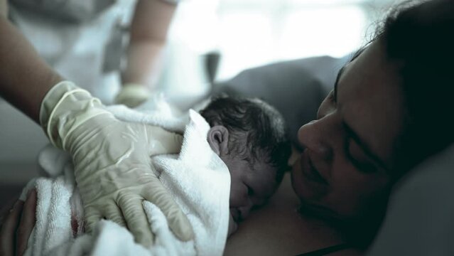 Capturing the initial seconds of a newborn's life, this authentic scene shows a baby resting on the mother's skin right after childbirth, symbolizing the beginning of life