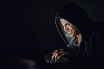 Dark, basement and man at laptop for hacking, online programming and cybersecurity at night....