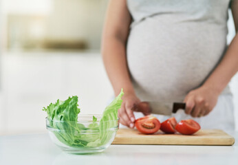 Woman, pregnant and cutting vegetables in home, nutrition and vitamin for growth of baby. Female person, hands and organic tomatoes or food for health, salad and healthy diet for maternity in kitchen