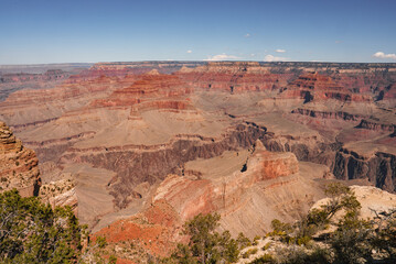 Expansive view of Grand Canyon, Arizona, USA, showcases stunning red rock layers, clear sky, deep gorges, rugged terrain. No people visible, untouched beauty captured.