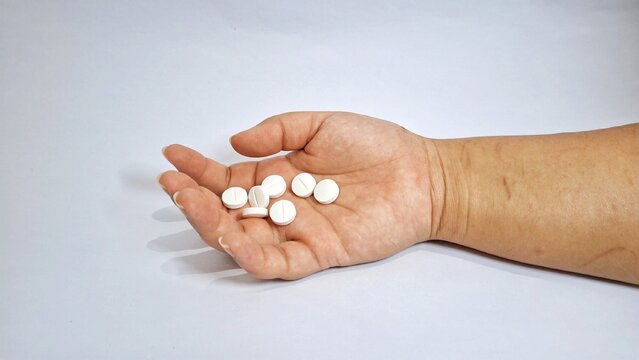 Isolated hand lying on the ground clutching drugs. suicidal concepts, depression and self harm.