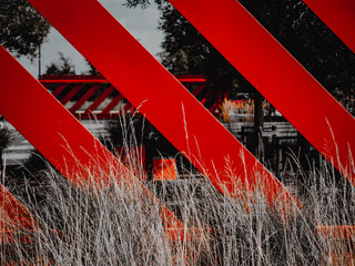 Diagonal vivid red abstract bold garden fence with dried grasses in foreground