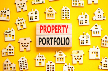 Property portfolio symbol. Concept words Property portfolio on beautiful wooden blocks. Wooden model of houses. Beautiful yellow background. Business Property portfolio concept. Copy space.