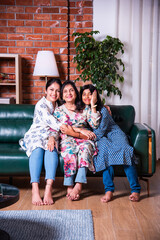 Three generations of Indian Asian females family smiling and looking at camera.